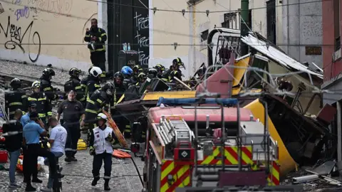 Getty Images Rescuers and firefighters operate at the scene after the Gloria funicular cable railway derailed in Lisbon, Portugal